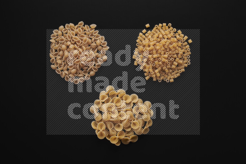 Different pasta types in bunches on black background