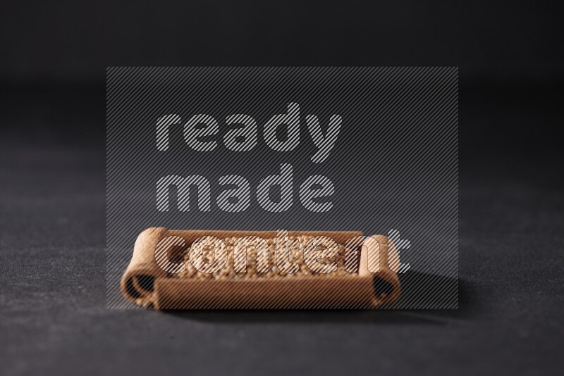 A single square of cinnamon sticks full of mustard seeds on black flooring