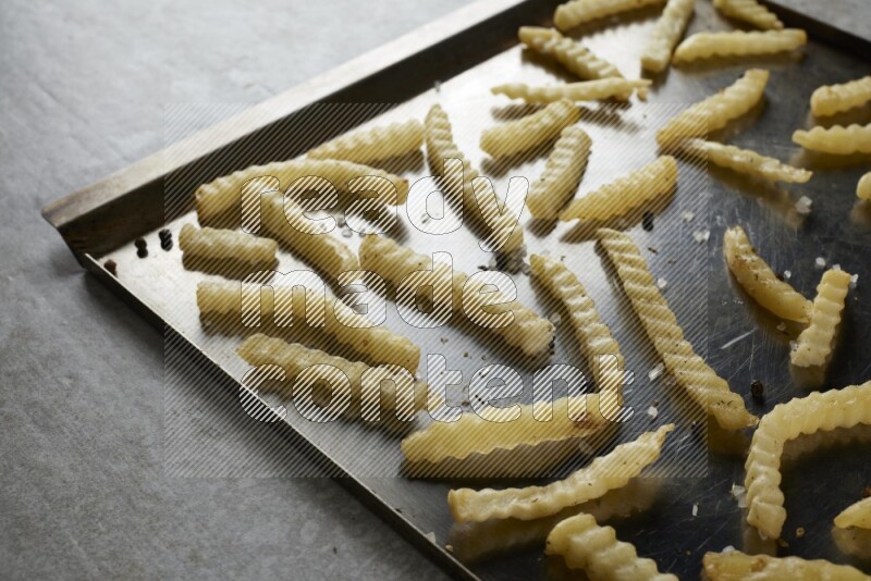 crinkle fries in a black stainless steel rectangle tray on grey textured counter top