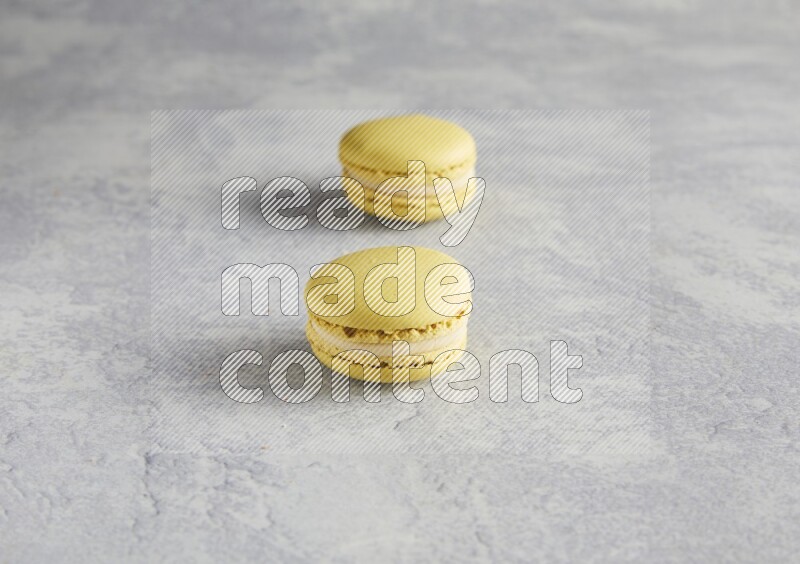 45º Shot of two Yellow Lime macarons  on white  marble background