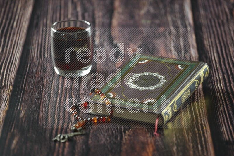 Quran with dates, prayer beads and different drinks all placed on wooden background