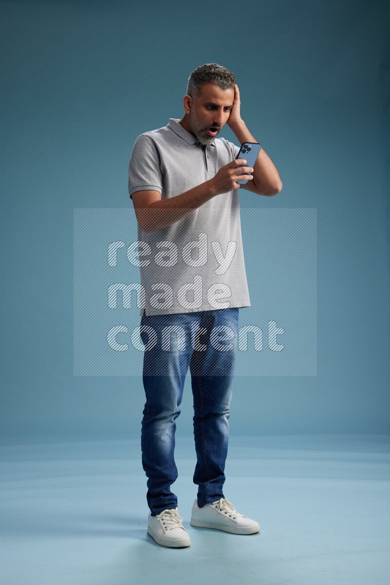 Man Standing texting on phone on blue background