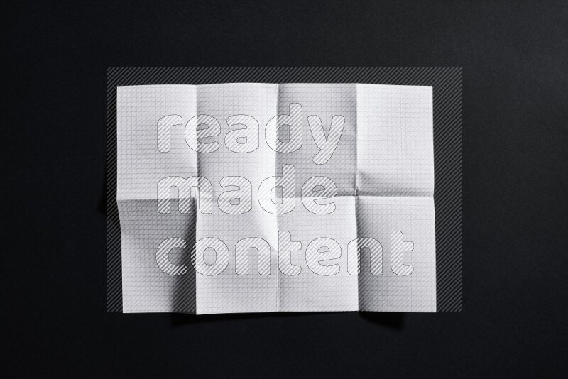 Folded notebook sheet on black background