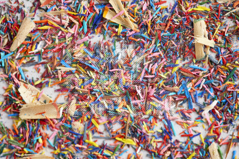 This image showcases a vibrant multicolored pencil shavings scattered on grey background