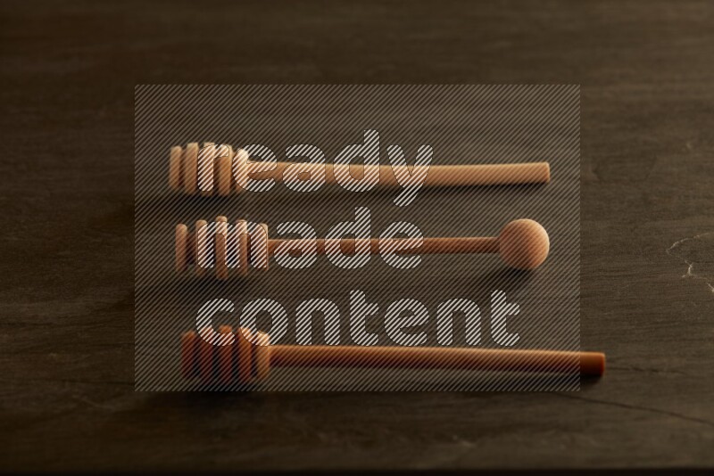 Wooden honey dipper on black slate background