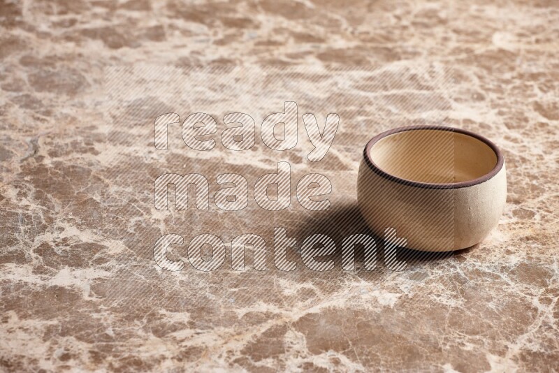 A beige pottery oven bowl on beige marble background
