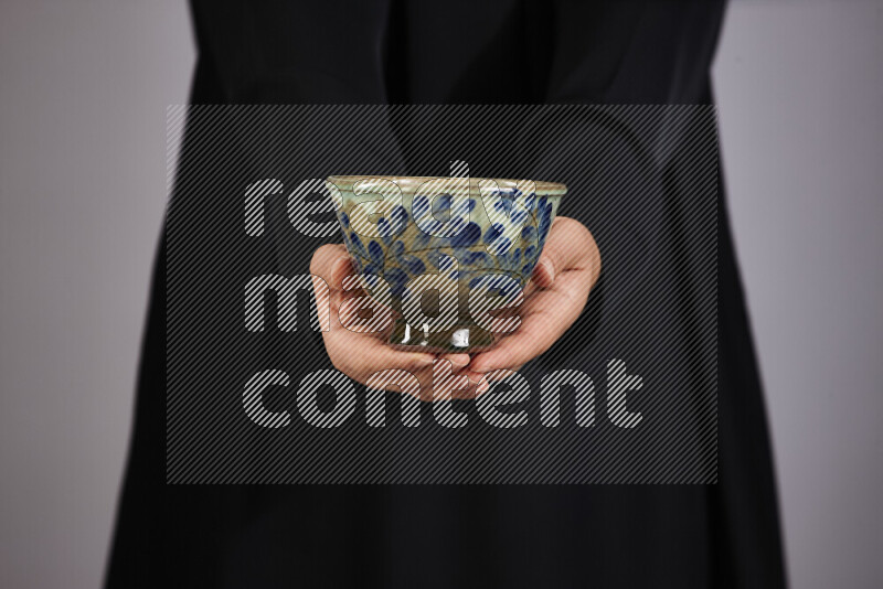 A woman in black abaya holding different pottery essentials in different positions