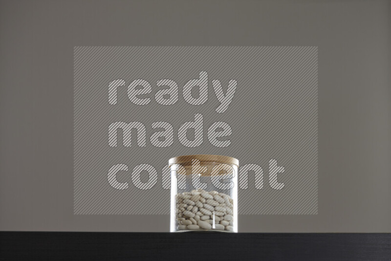 White beans in a glass jar on black background