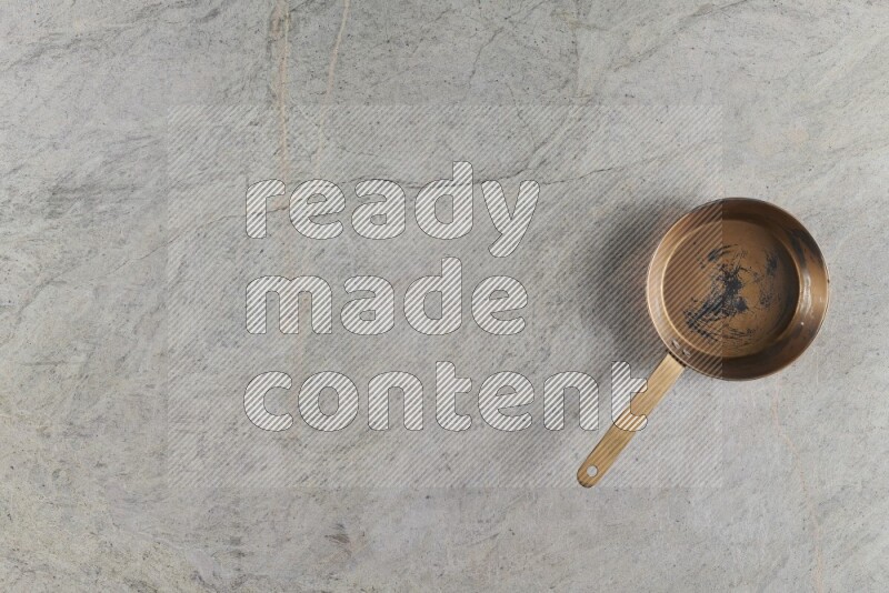 A small copper pan on grey marble background