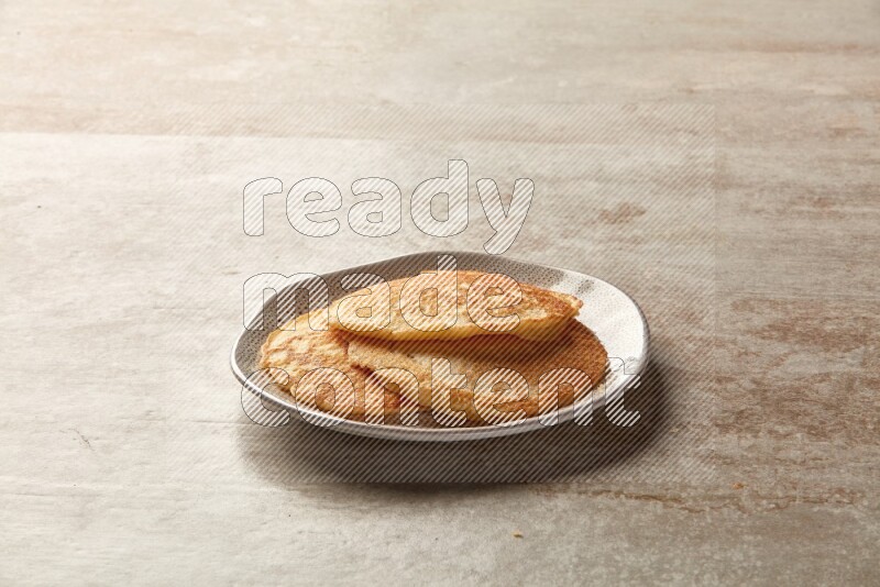 Three stacked plain pancakes in an irregular plate on beige background