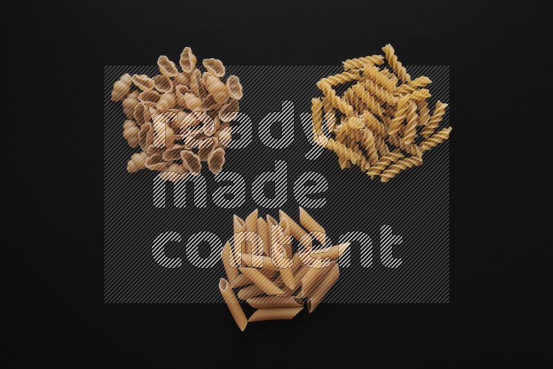 Different pasta types in bunches on black background