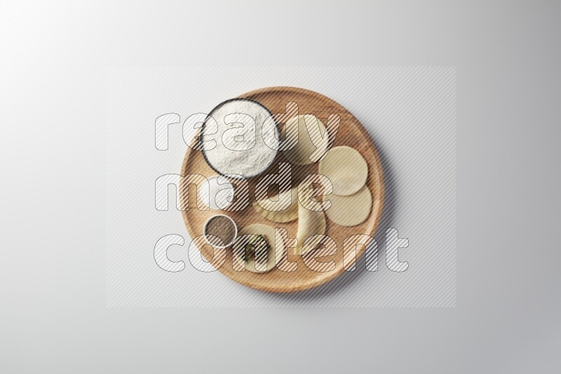 two closed sambosas and one open sambosa filled with meat while flour, salt, and black pepper aside in a wooden dish on a white background