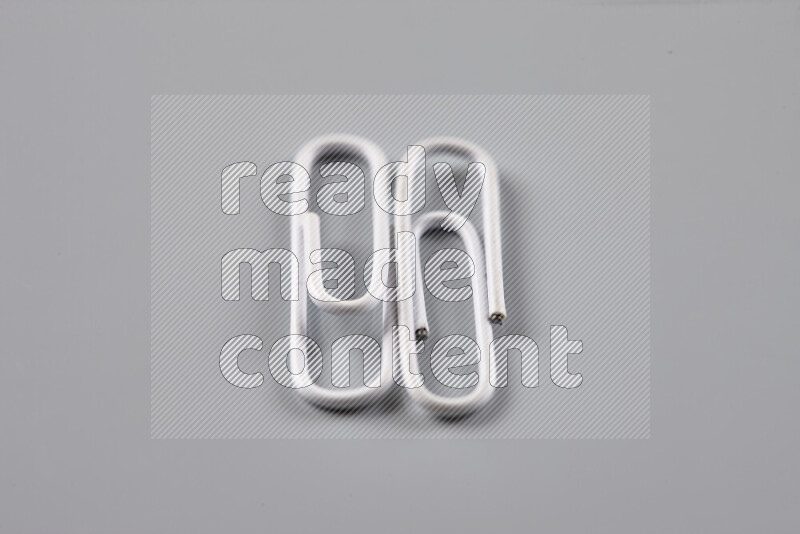 White paper clips isolated on a grey background