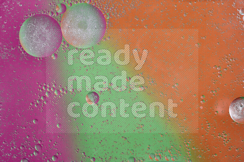 Close-ups of abstract oil bubbles on water surface in shades of orange, green and pink