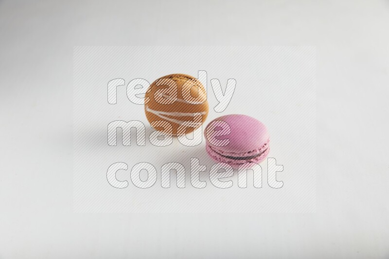 45º Shot of of two assorted Brown Irish Cream, and Purple Strawberry macarons on white background