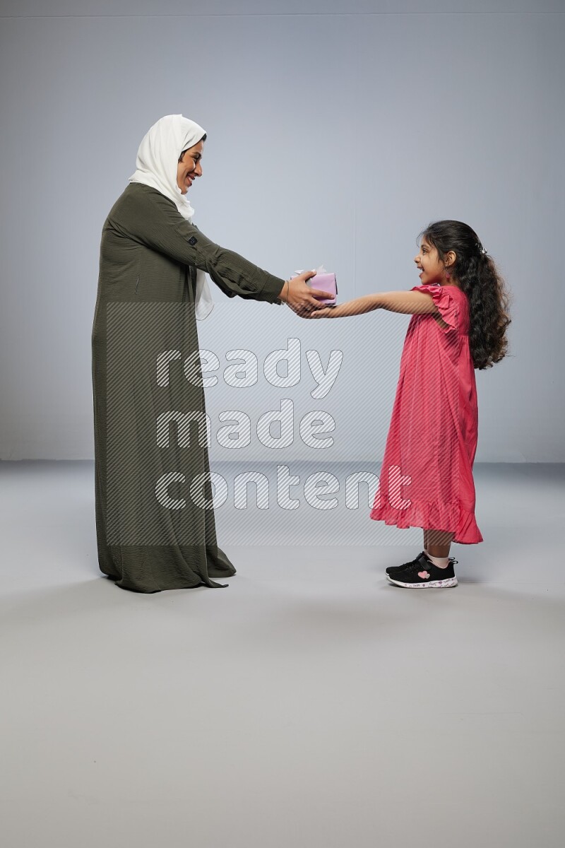 A girl giving a gift to her mother on gray background
