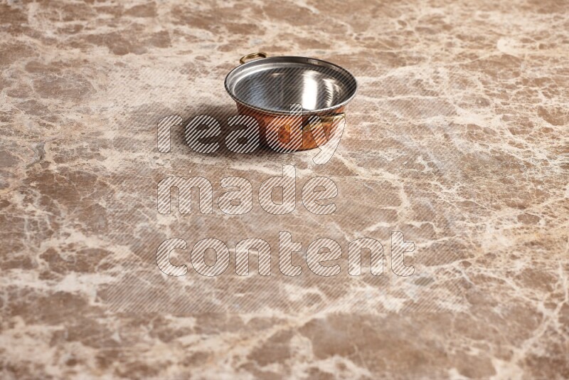 A small copper pot on beige marble background