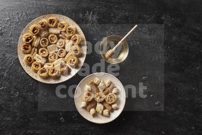 Oriental sweets in pottery plates with honey in a dark setup