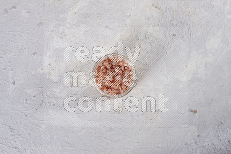 A glass jar full of coarse himalayan salt crystals on white background