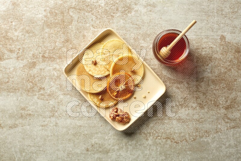 Five stacked dried orange mini pancakes in a rectangular plate on beige background