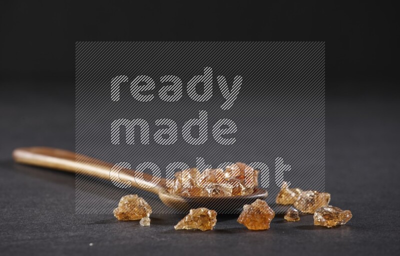 ملعقة خشبية كبيرة ممتلئة بقطع الصمغ العربي علي خلفية سوداء