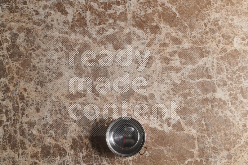 A small copper pot on beige marble background