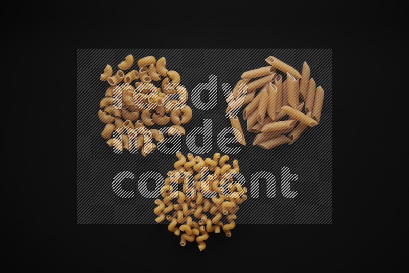 Different pasta types in bunches on black background