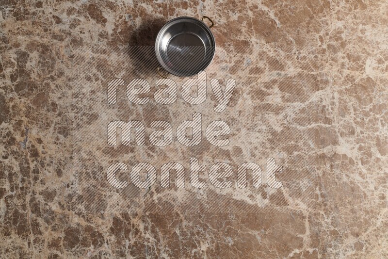 A small copper pot on beige marble background