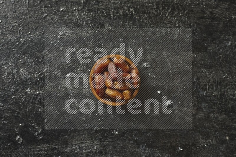 Dates in wooden bowls in a dark setup