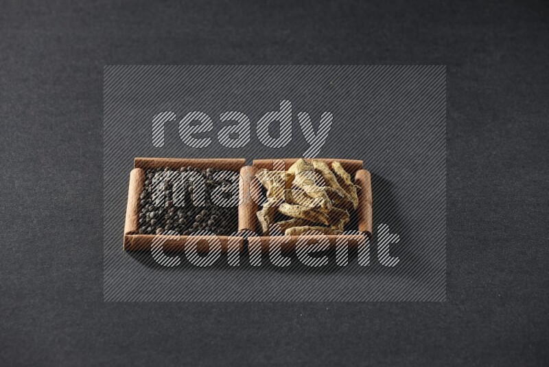 2 squares of cinnamon sticks full of black peppers and turmeric fingers on black flooring