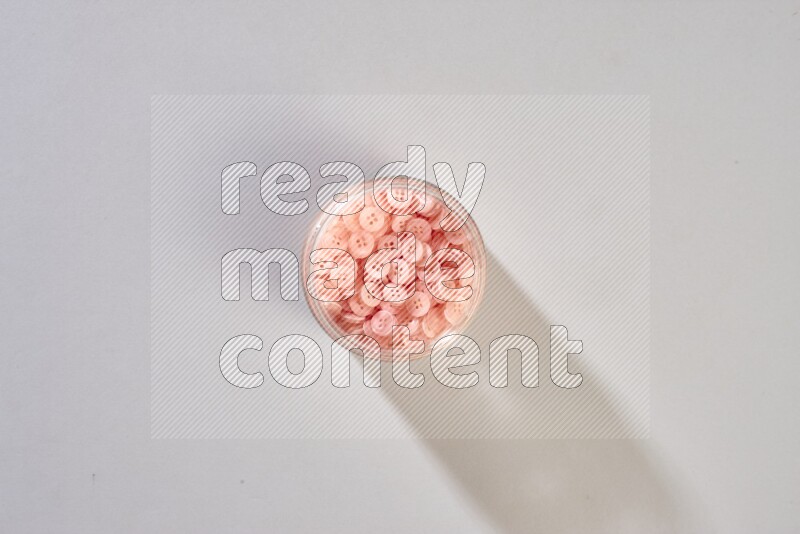 Colored buttons in a glass jar on grey background