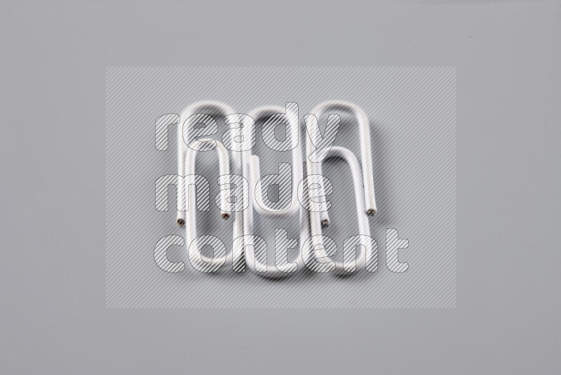 White paper clips isolated on a grey background