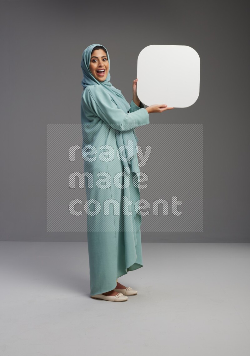 Saudi Woman wearing Abaya standing holding social media sign on Gray background