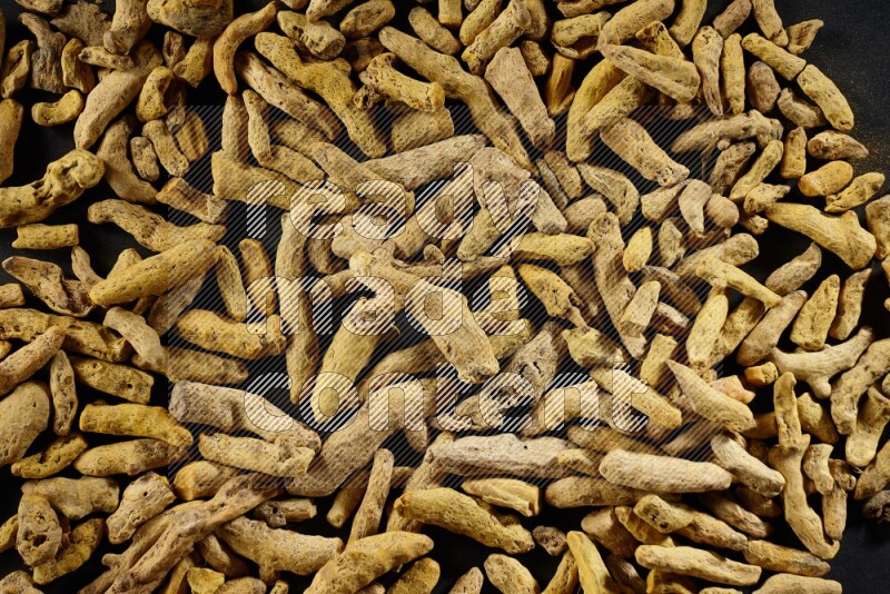Dried turmeric fingers on black flooring