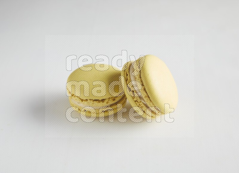 45º Shot of two Yellow Lime macarons on white background