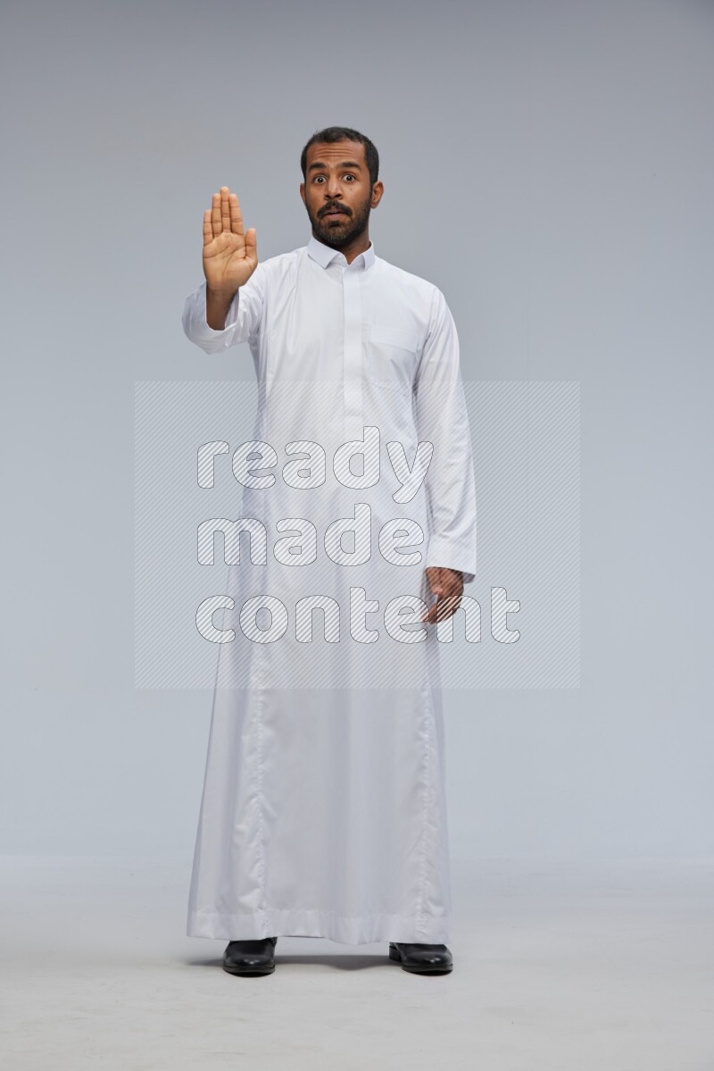 Saudi man Wearing Thob standing interacting with the camera on Gray background