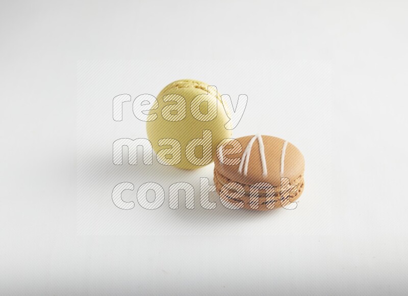 45º Shot of of two assorted Brown Irish Cream, and Yellow Lime macarons on white background