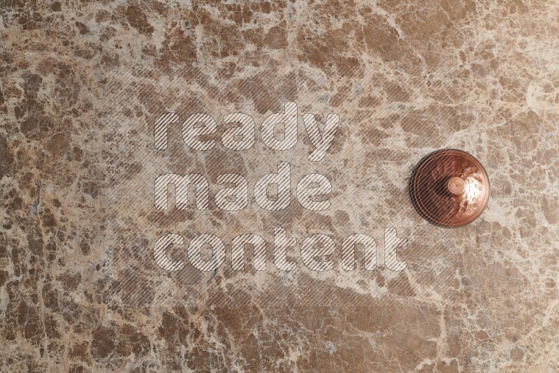 A small copper pot on beige marble background