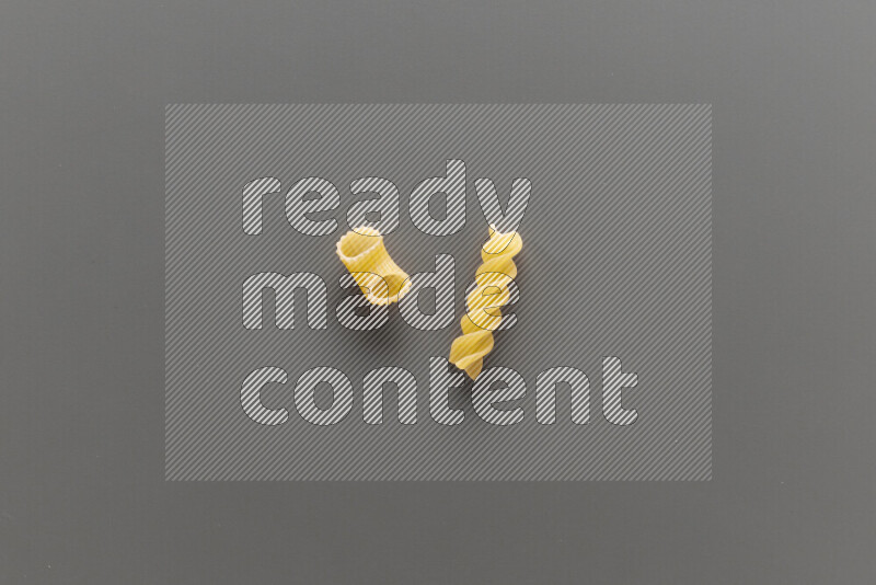 Elbow pasta with other types of pasta on grey background