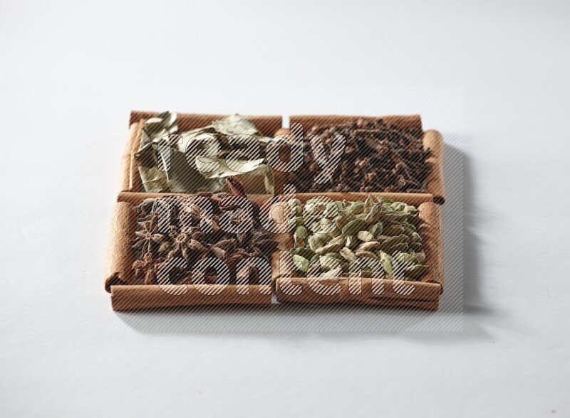 4 squares of cinnamon sticks full of cardamom, star anise, cloves and bay laurel leaves on white flooring