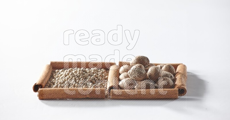 2 squares of cinnamon sticks full of white pepper and nutmegs on white flooring