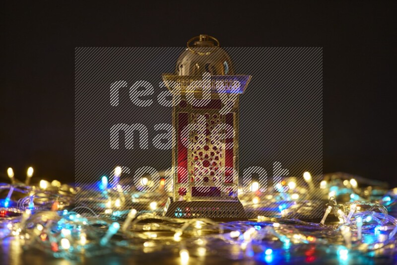 A traditional ramadan lantern surrounded by glowing fairy lights in a dark setup