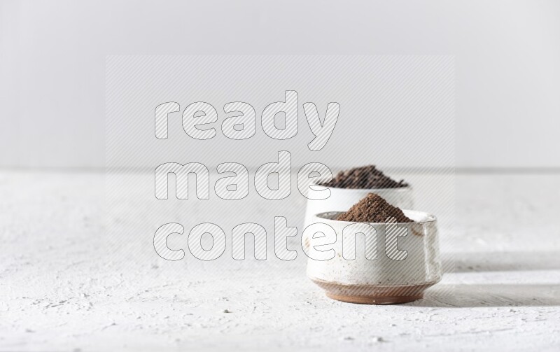 وعاءين من السيراميك بيج اللون، أحدهما مملوء بالقرنفل والآخر مملوء بالبودرة على أرضية بيضاء