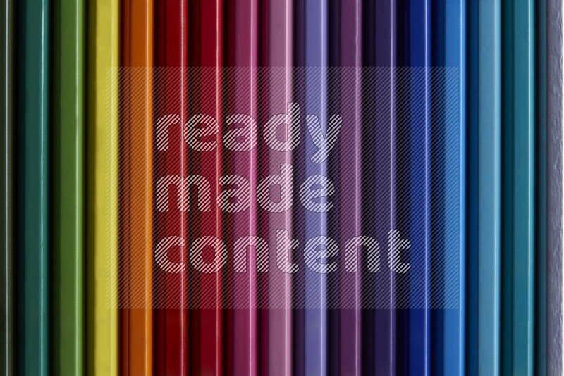 مجموعة من أقلام الرصاص الملونة مرتبة لتعرض تدرجا من الألوان المختلفة علي خلفية رمادية