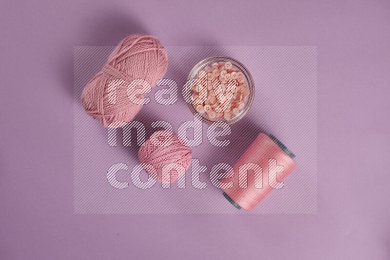 A pink and purple collection of sewing and tailoring tools arranged on a purple background