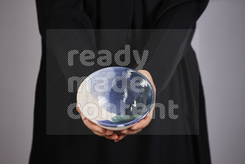 A woman in black abaya holding different pottery essentials in different positions