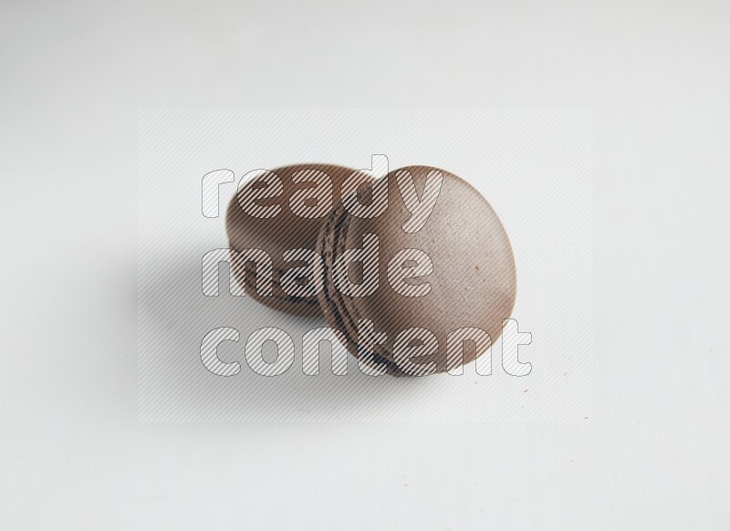 45º Shot of two Brown Dark Chocolate macarons on white background
