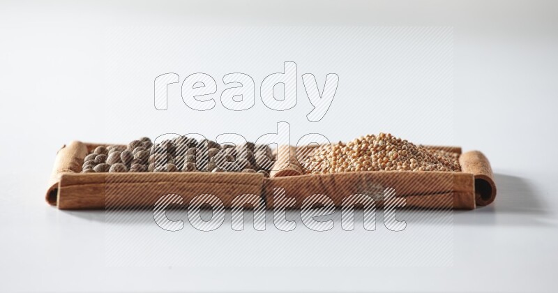 2 squares of cinnamon sticks full of mustard seeds and allspice on white flooring