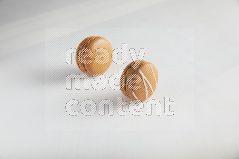 45º Shot of of two assorted Brown Irish Cream, and Brown Maple Taffy macarons  on white background