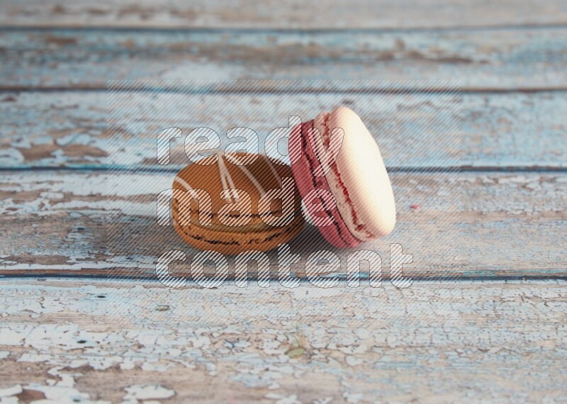 45º Shot of of two assorted Brown Irish Cream, and Pink Litchi Raspberry macarons on light blue background
